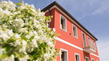Un edificio rosso con modanature bianche e un balcone con piante.