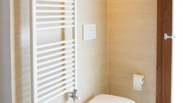 A bathroom with a white bathtub, a white toilet, and a towel rack.