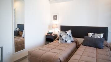 Habitación de hotel con dos camas, una mesita de noche, una lámpara, un cuadro enmarcado y un espejo.