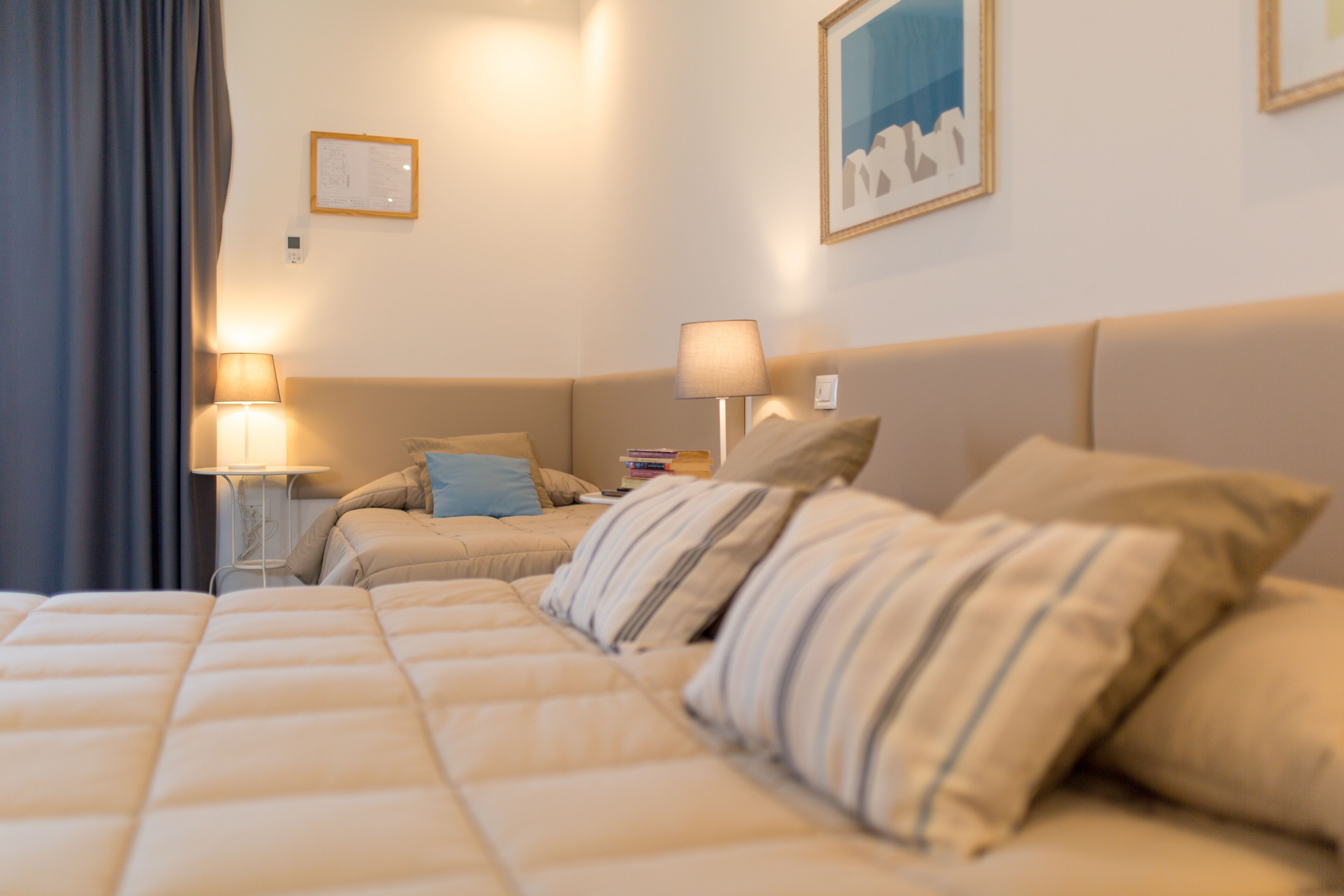 Een hotelkamer met een groot bed, twee nachtkastjes met lampen, een hoofdeinde en een inlijstbaar kunstwerk aan de muur.