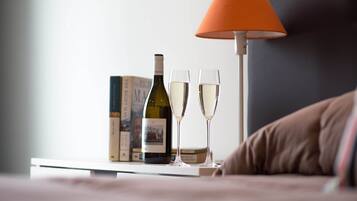 A bedside table with a wine bottle, two glasses, and a book.