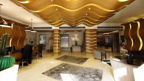 A modern lobby with a reception desk, seating area, and a large decorative wall. - WH Hotel (Beirut)