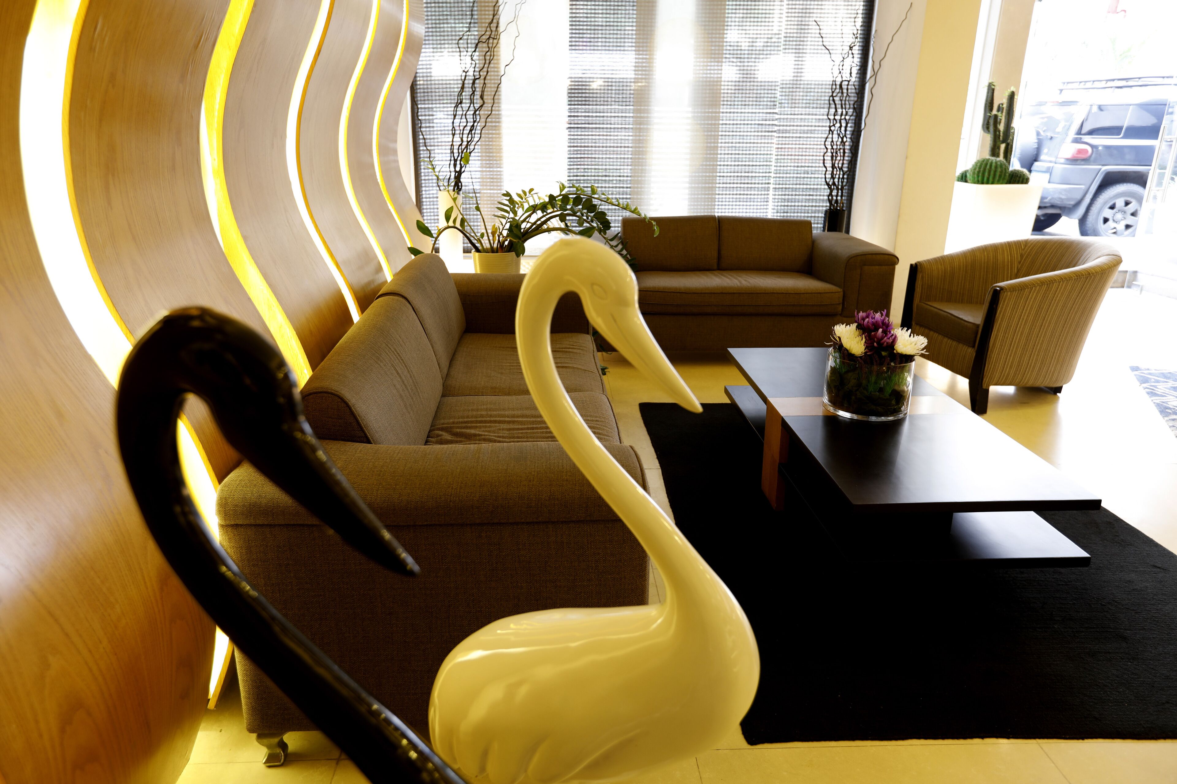 A modern living room with a sofa, a dining table, and a unique white swan sculpture.