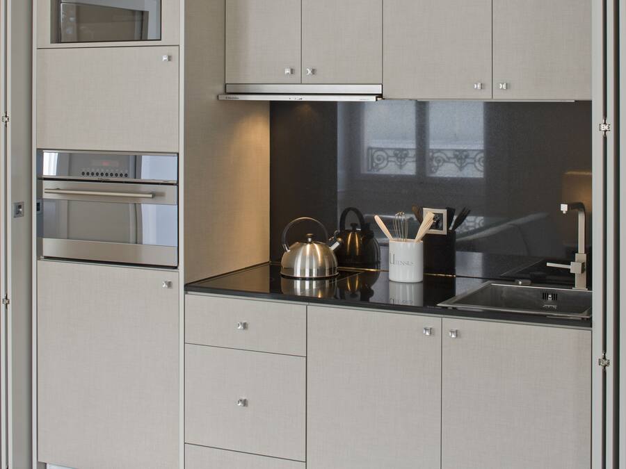 Una cucina moderna con elettrodomestici integrati, un bollitore e una macchina per il caffè sul piano di lavoro.