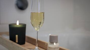Una copa de vino blanco sobre una bandeja con una vela encendida y una botella de perfume.