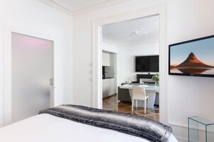 Una habitación de hotel moderna con una cama, un escritorio y un televisor.