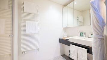 Un baño moderno con un lavamanos blanco, espejo y toalleros.