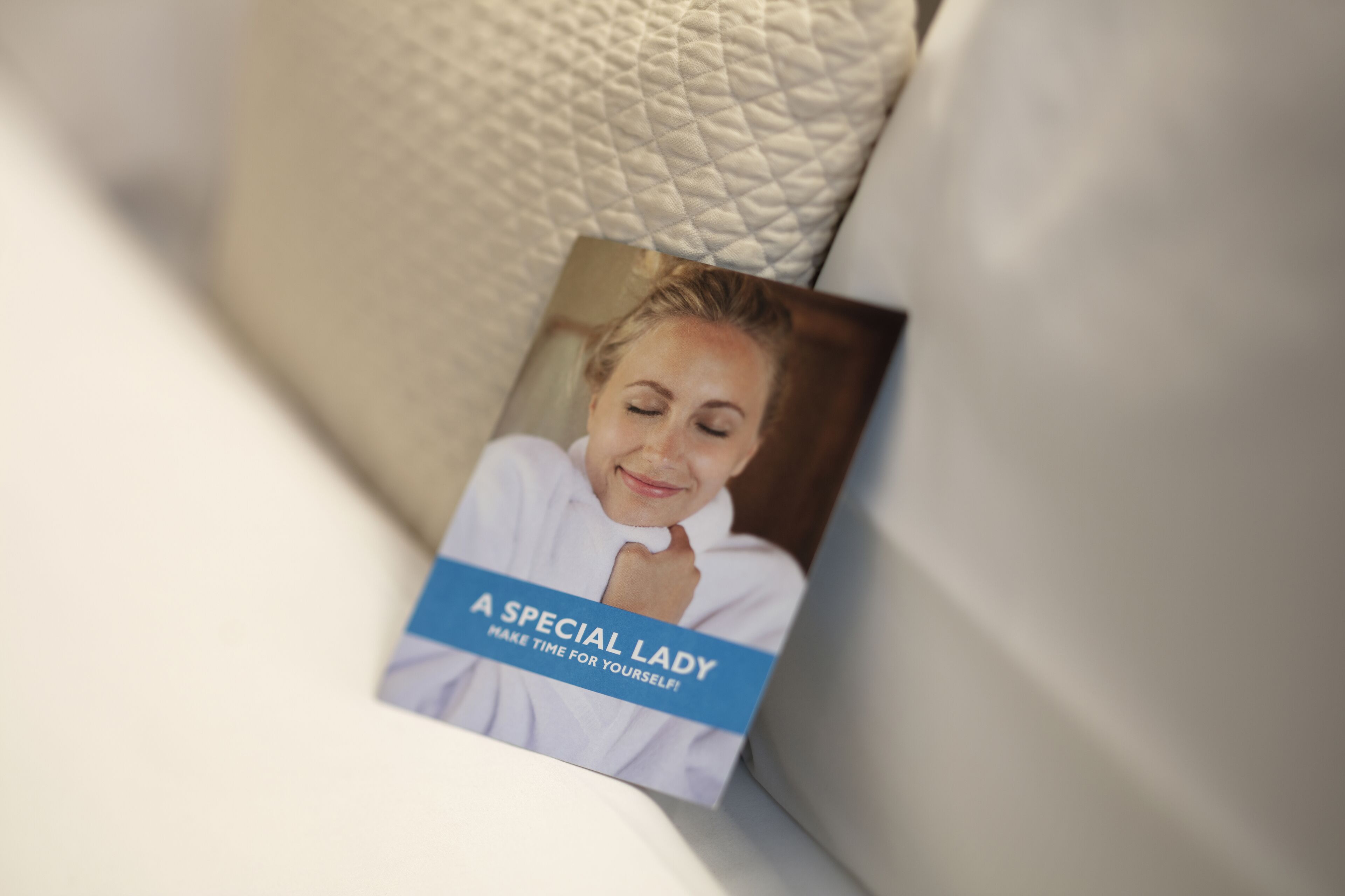 Un folleto con el título "A Special Lady" sobre un sofá blanco con funda acolchada.