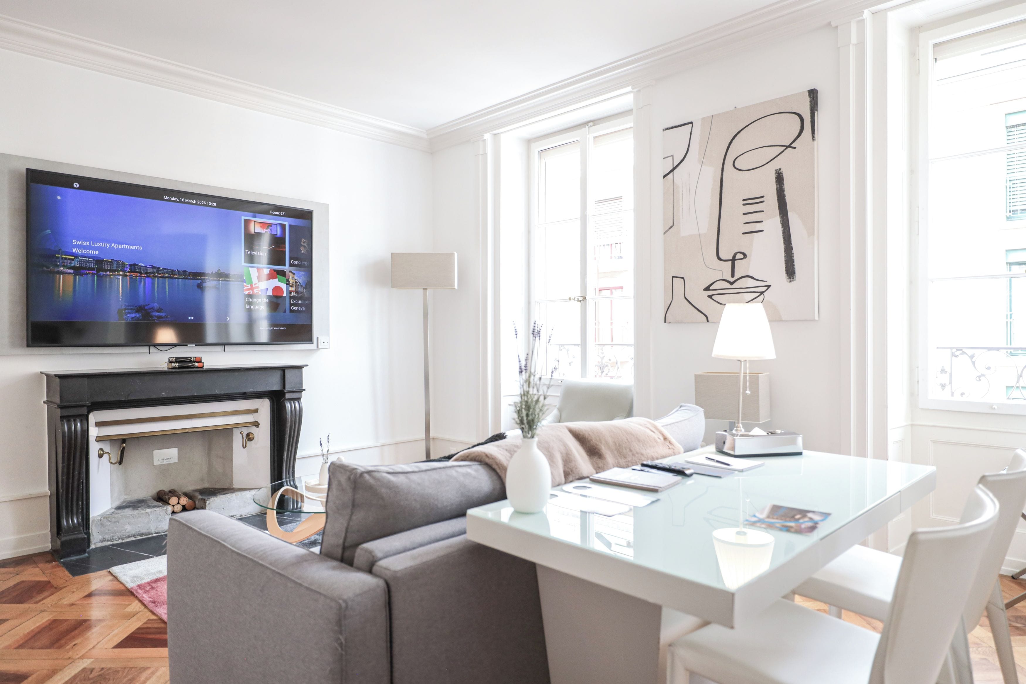 A modern living room with a television, a fireplace, a dining area with a glass table, and a large window.