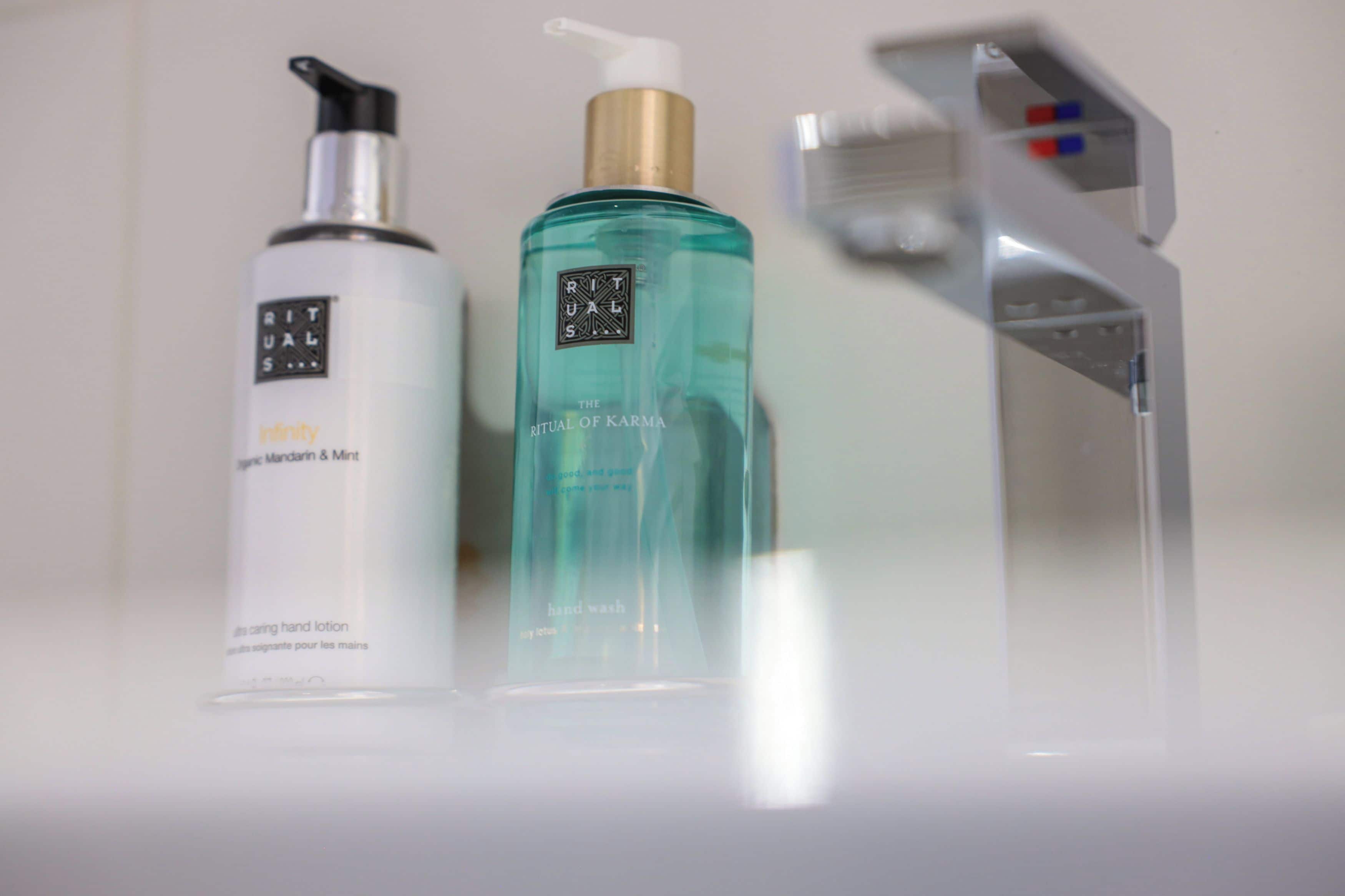 Un baño con un lavamanos blanco, dispensador de jabón y botella de jabón líquido.