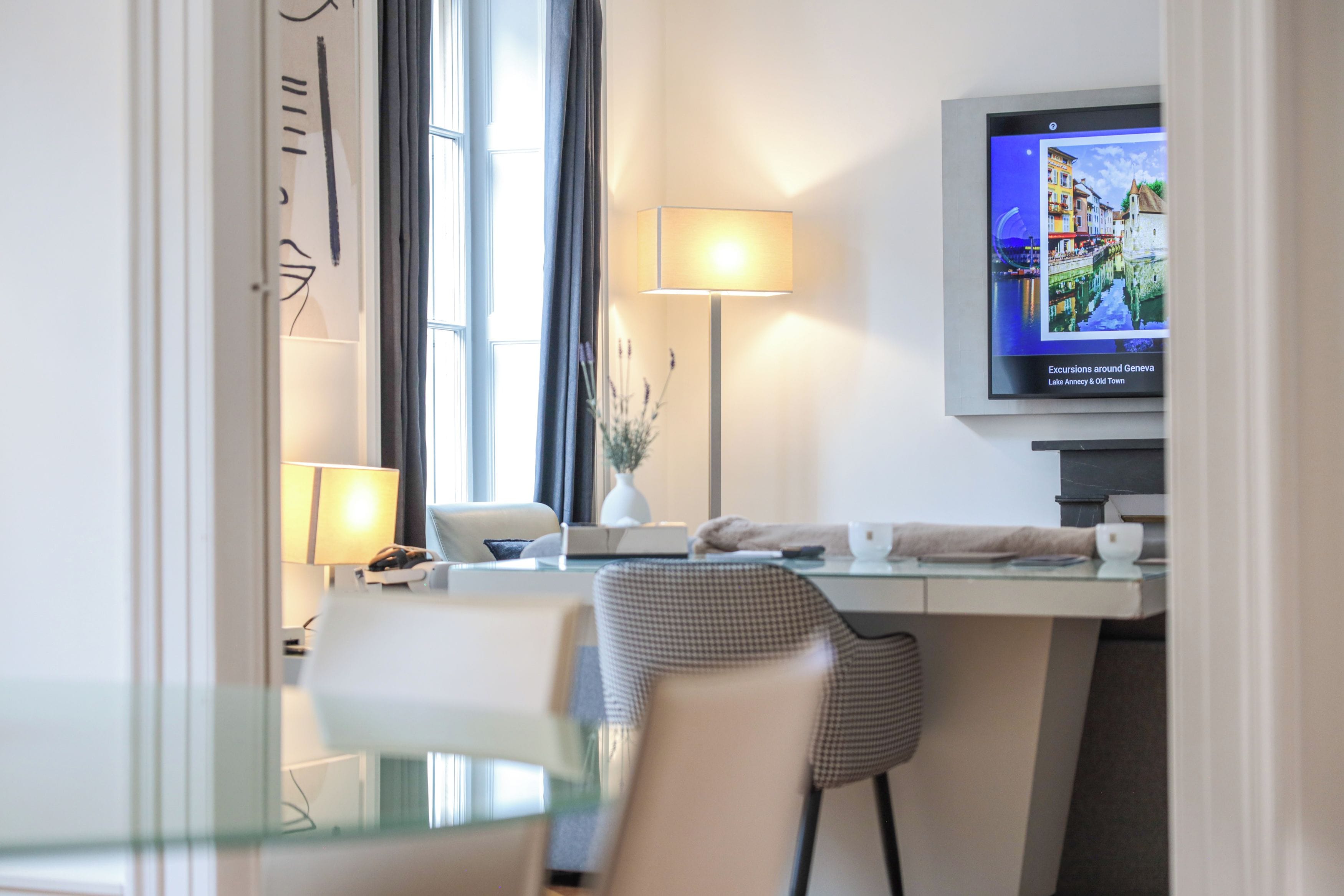 Een hotelkamer met een bureau, stoel, televisie en een raam met gordijnen.