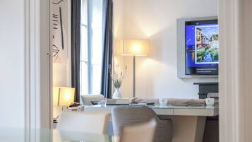 Een hotelkamer met een bureau, stoel, televisie en een raam met gordijnen.