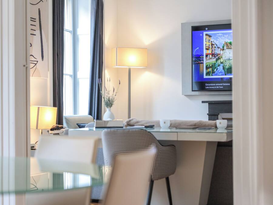 Een hotelkamer met een bureau, stoel, televisie en een raam met gordijnen.