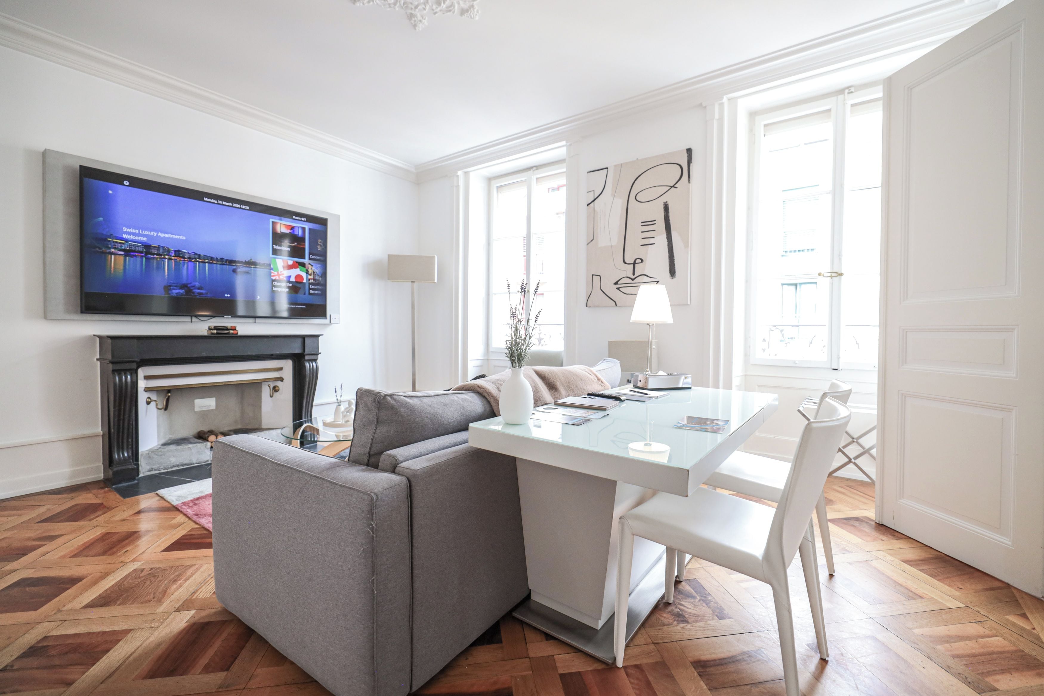 A modern living room with a flat-screen TV, a fireplace, a sofa, a dining table, and a large window.