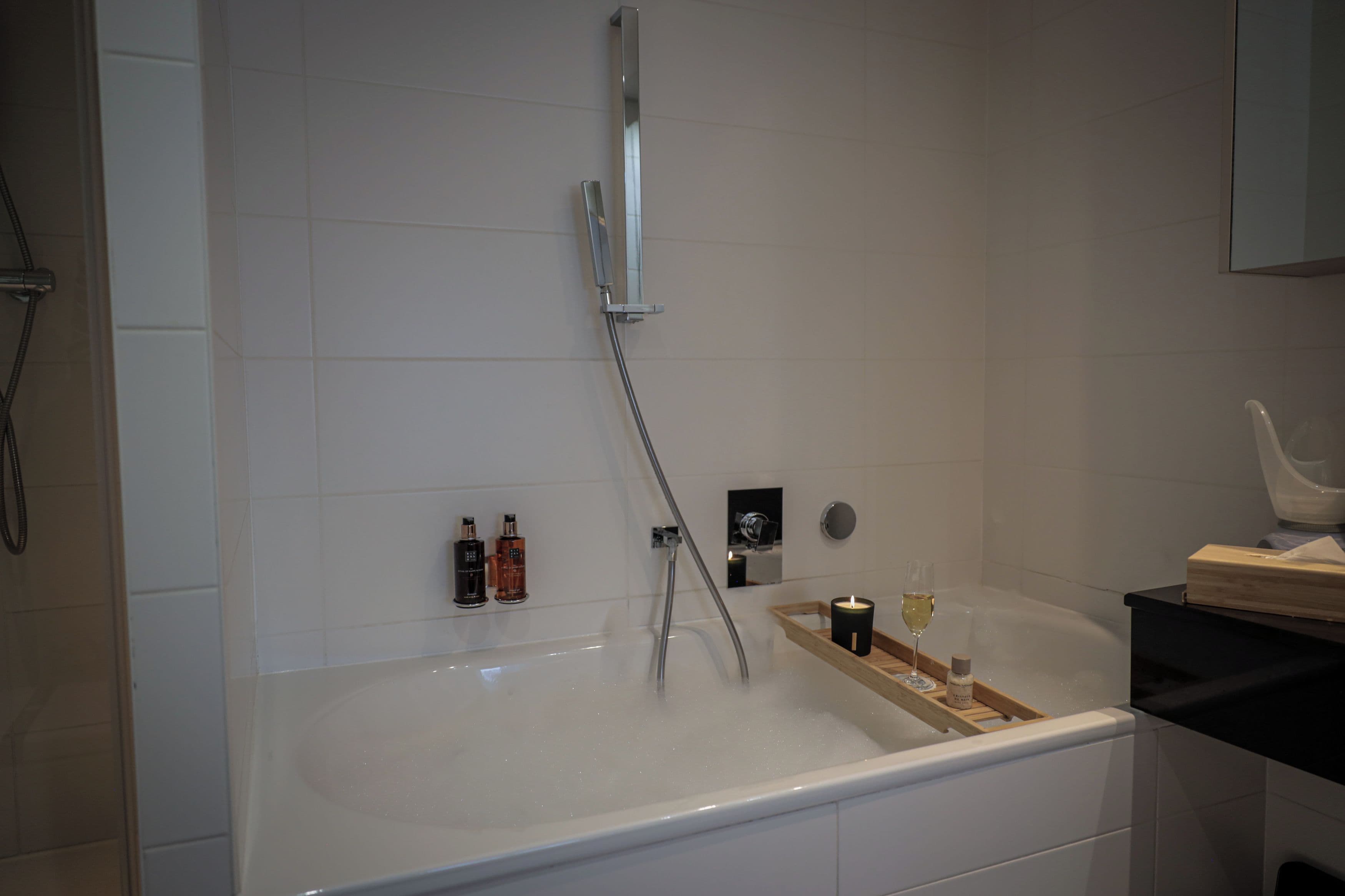 A modern bathroom with a bathtub, a handheld showerhead, and a vanity with a mirror.