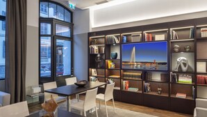 A modern library with a large bookshelf, a dining area, and a view of a cityscape through large windows. - Swiss Luxury Apartments Geneva (Geneva)