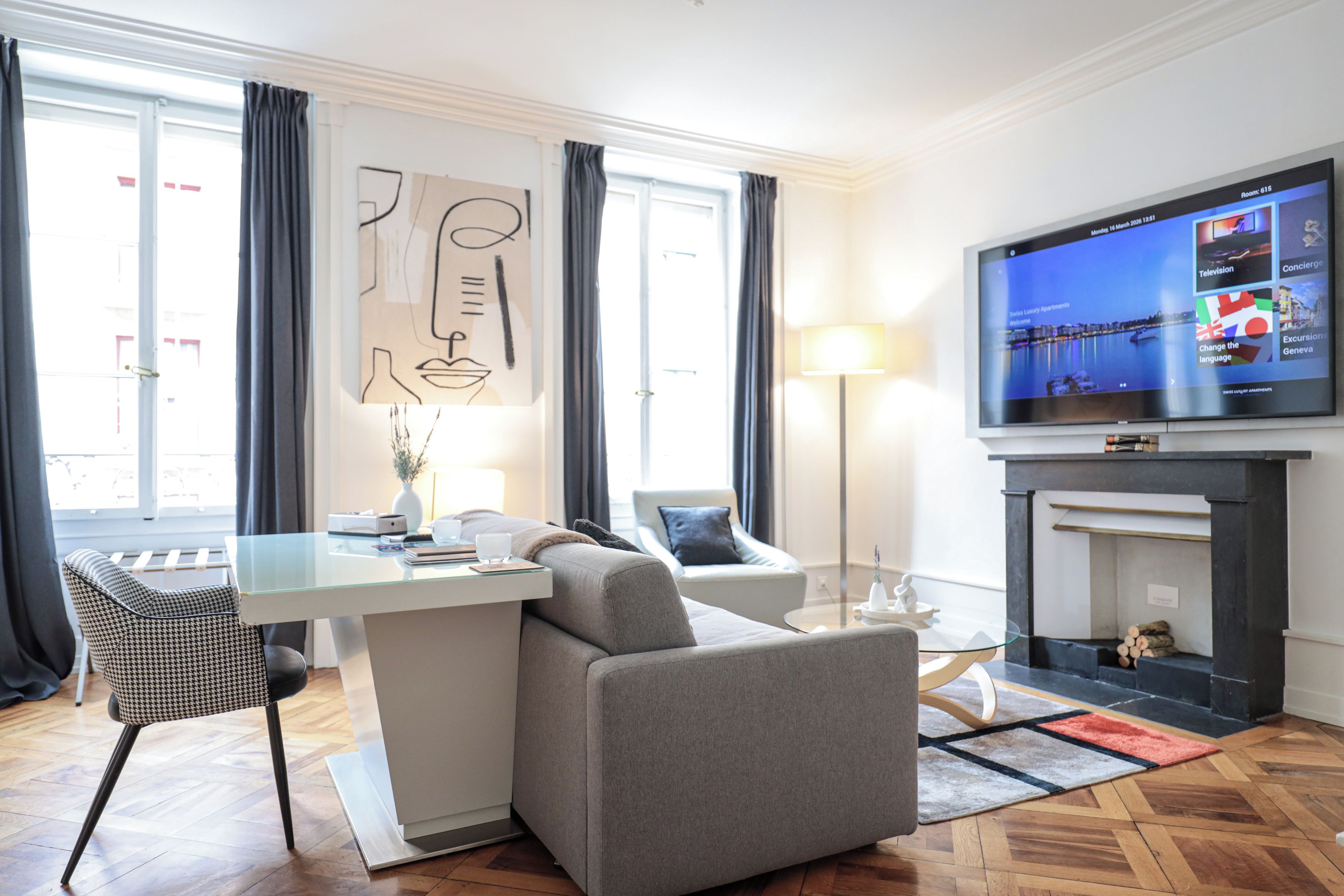 A modern living room with a flat-screen TV, a fireplace, a sofa, a dining table, and a large window with curtains.