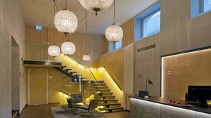 A modern hotel lobby with a staircase, a reception desk, and pendant lighting. - Swiss Luxury Apartments Geneva (Geneva)