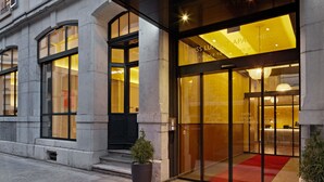 A modern hotel entrance with large glass doors, a red carpet, and a potted plant. - Swiss Luxury Apartments Geneva (Geneva)