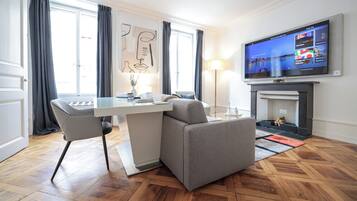 Una habitación de hotel moderna con zona de comedor, sofá, televisor de pantalla plana y chimenea.