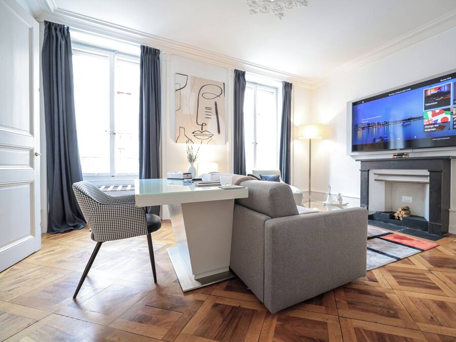 Una habitación de hotel moderna con zona de comedor, sofá, televisor de pantalla plana y chimenea.