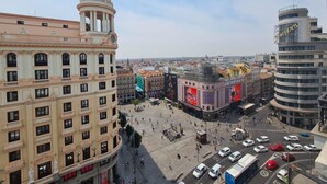 Una plaza con edificios históricos, un gran cartel publicitario y arquitectura moderna.