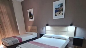 Habitación de hotel con dos camas, un ventanal grande y vista al mar.