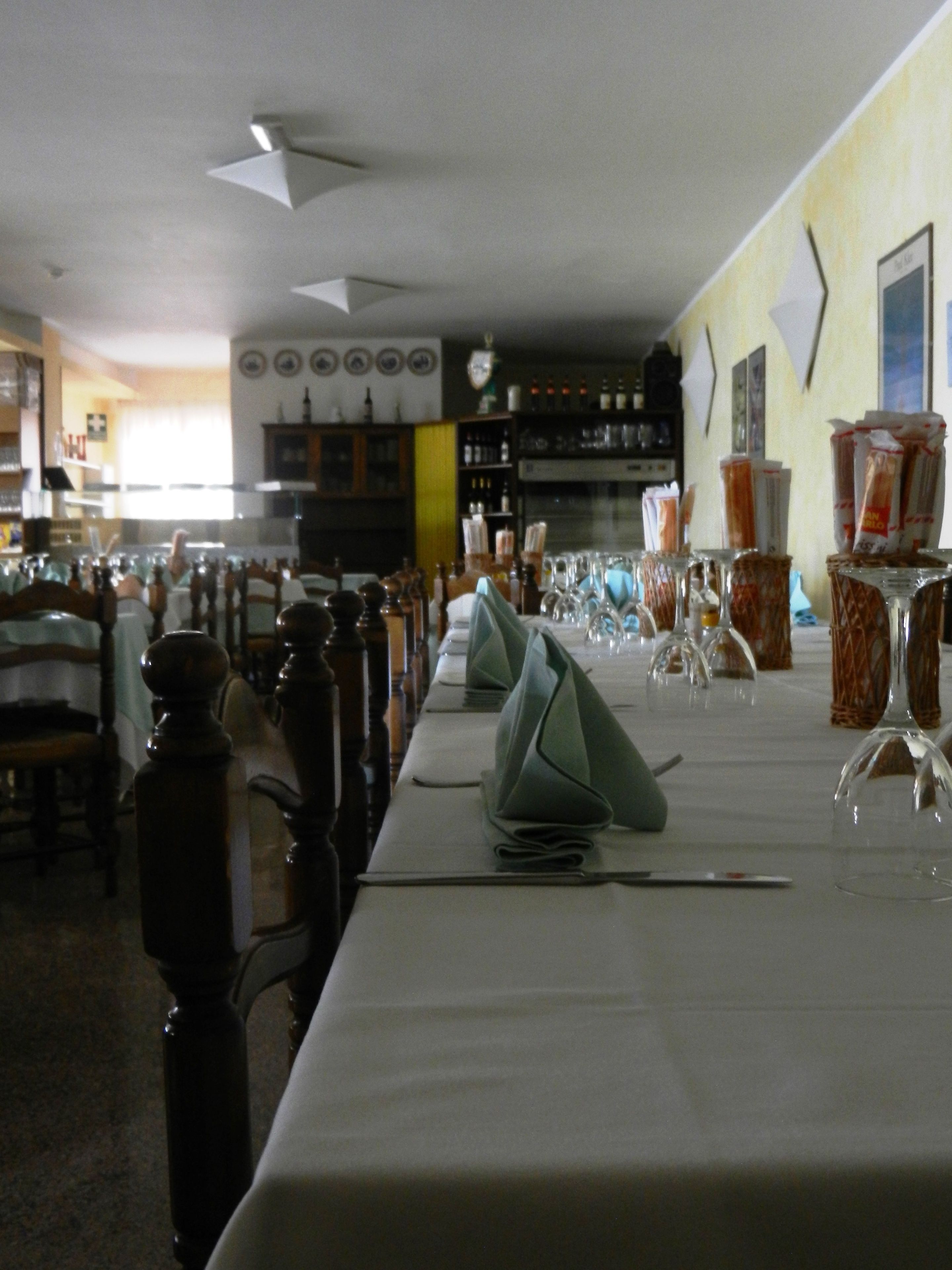 A dining area with tables set for a meal, chairs, and a bar area in the background.