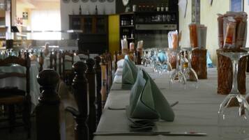 A dining area with tables set for a meal, chairs, and a bar area in the background.