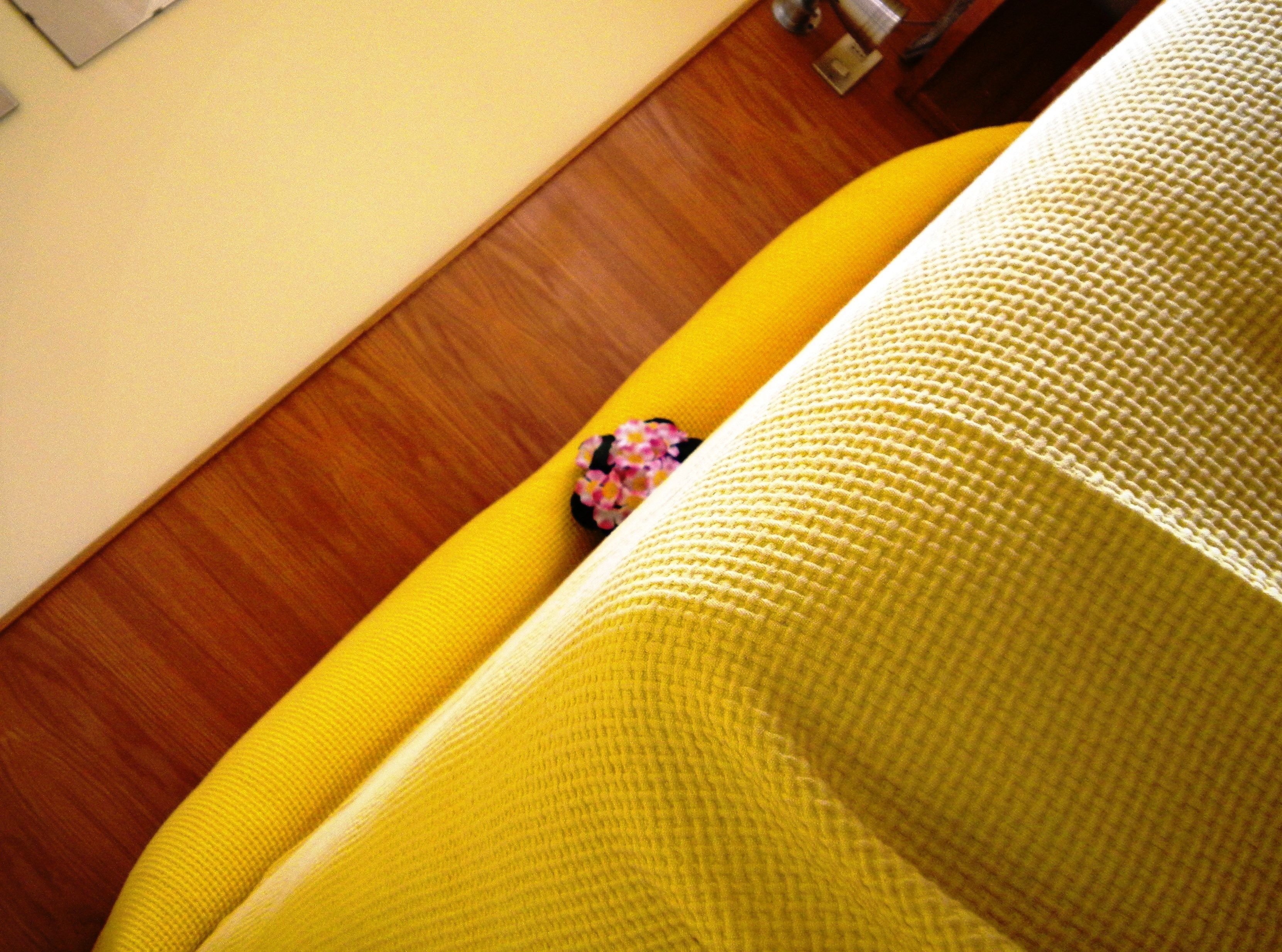 A yellow sofa with a textured fabric and a small decorative item on it.