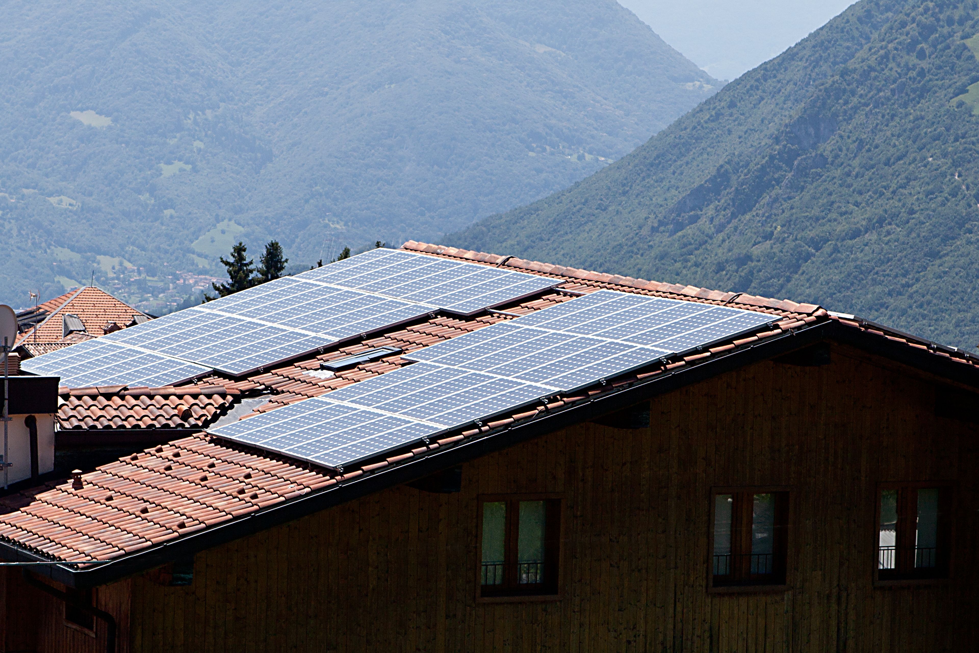 Ein Gebäude aus Holz mit einem Ziegeldach und Solaranlagen.