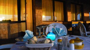 A table set for dining with a basket of bread, salt and pepper shakers, and a blue glass jar. - Hotel Albergo Al Milano (Bossico)