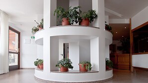 A multi-level atrium with potted plants on each floor. - Hotel Albergo Al Milano (Bossico)