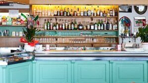 A bar with a variety of liquor bottles, glasses, and a potted plant. - Hotel Albergo Al Milano (Bossico)
