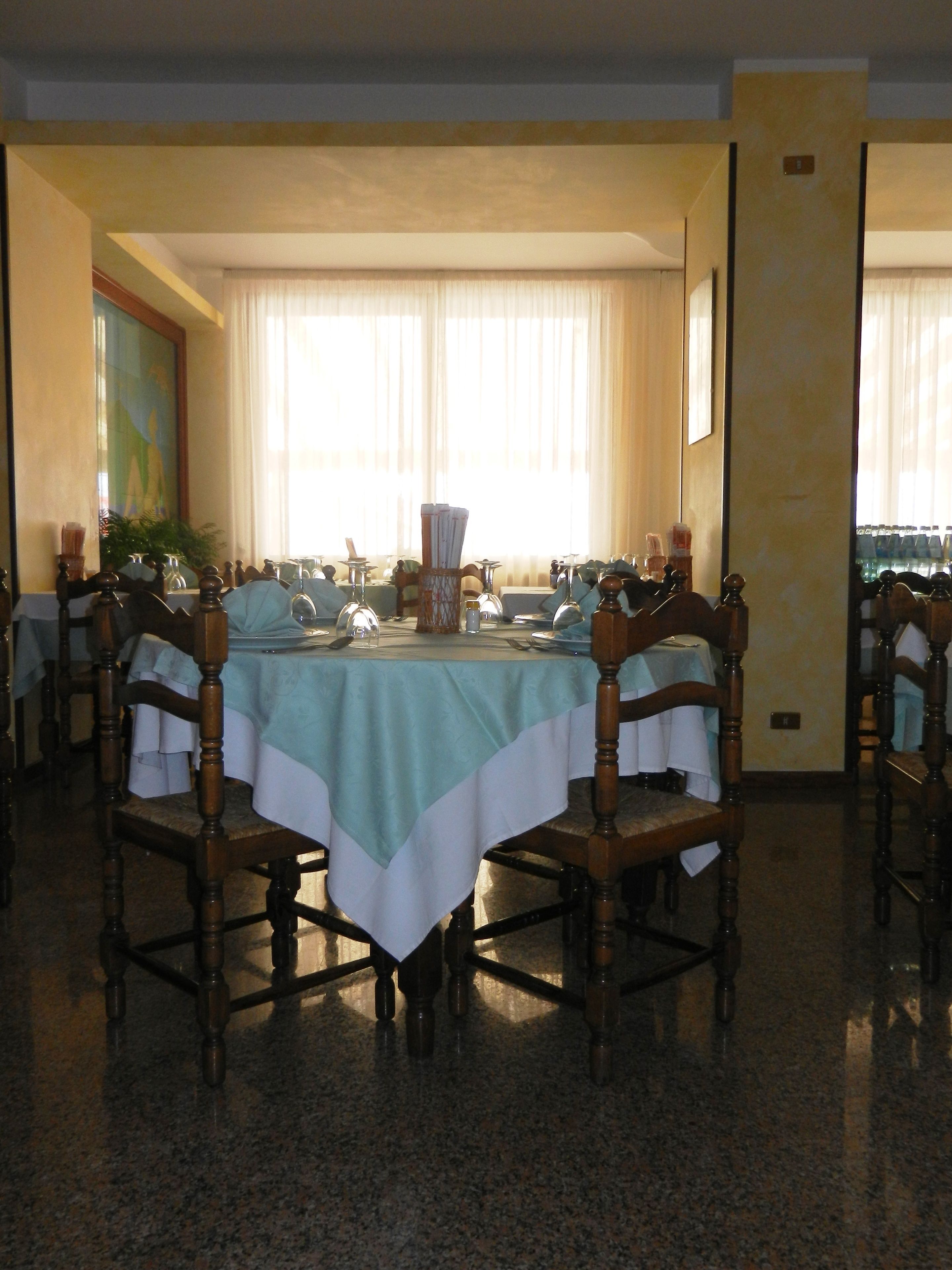 A dining area with a round table set for six, surrounded by wooden chairs.