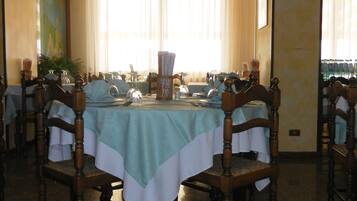 A dining area with a round table set for six, surrounded by wooden chairs.