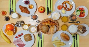 A breakfast table with various food items and utensils.