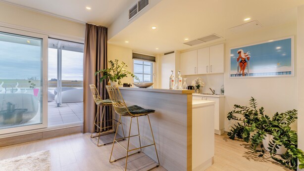A modern kitchen with a bar area, large windows, and a view of the outdoors.