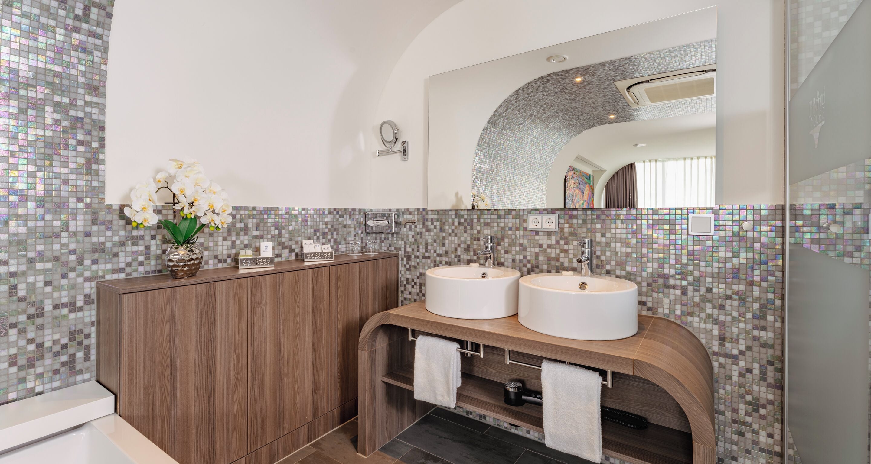 Un baño moderno con dos lavamanos, tocador y espejo.