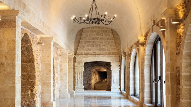 Un pasillo con paredes de piedra, chimenea y ventanas de arco.