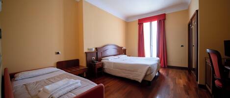 Habitación de hotel con dos camas, suelo de madera, cortina roja y televisor.