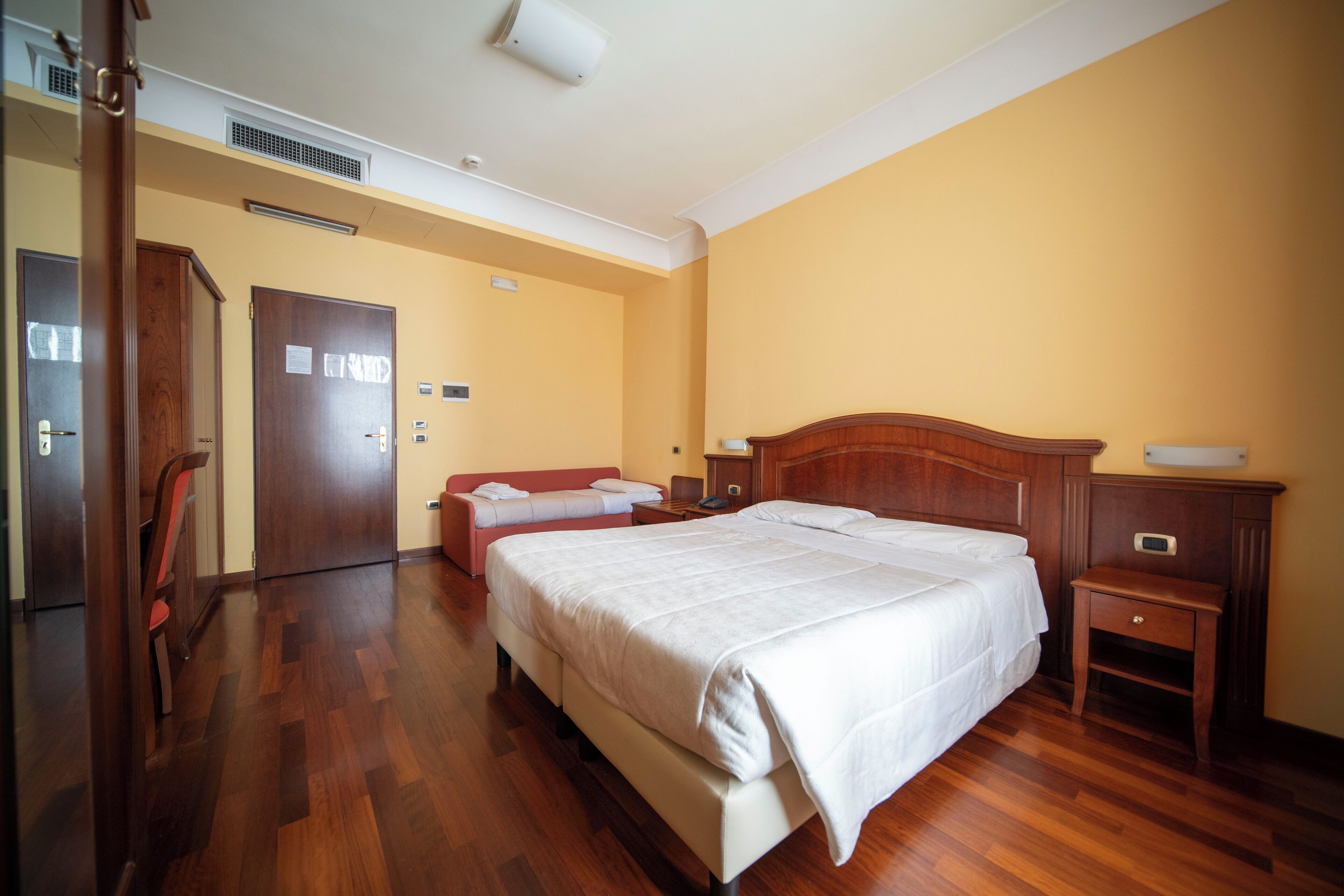 Una habitación de hotel con una cama grande, otra más pequeña, un escritorio y una silla.