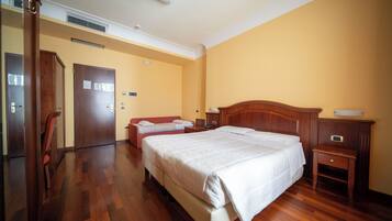 Una habitación de hotel con una cama grande, otra más pequeña, un escritorio y una silla.