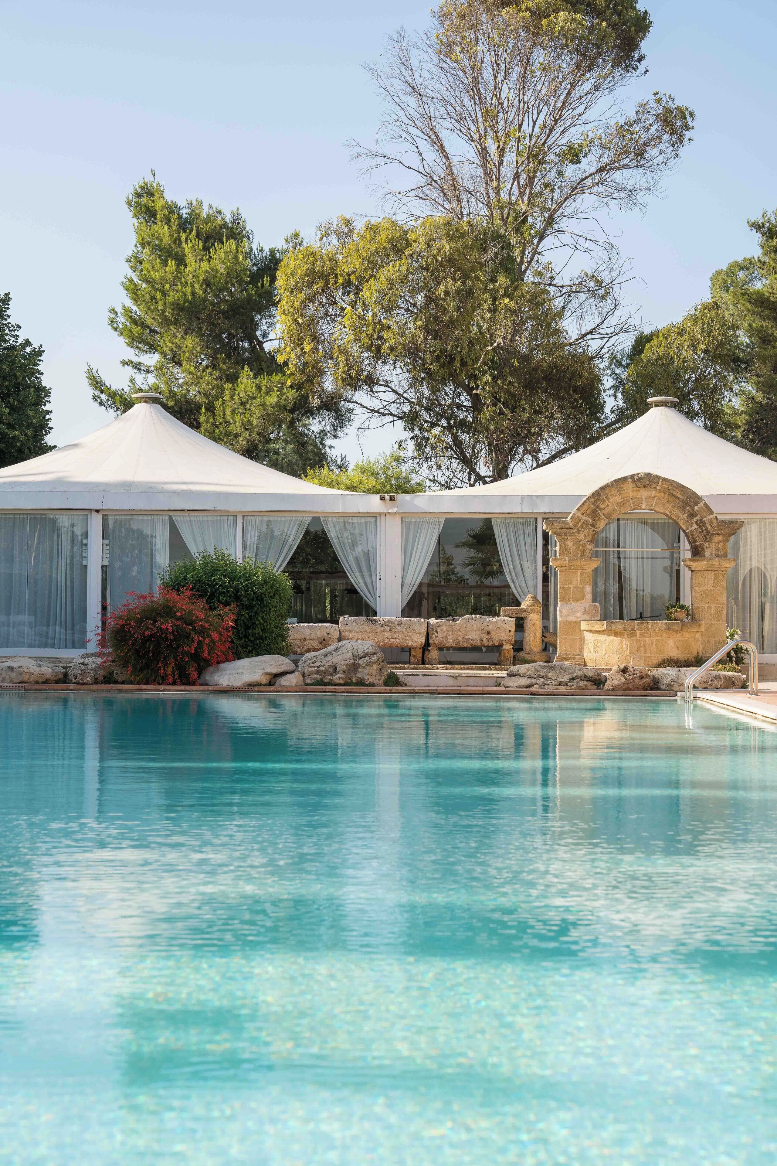 A pool area with a covered seating area and a stone structure.