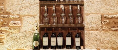 Una bodega con pared de piedra, estanterías de madera y botellas de vino.