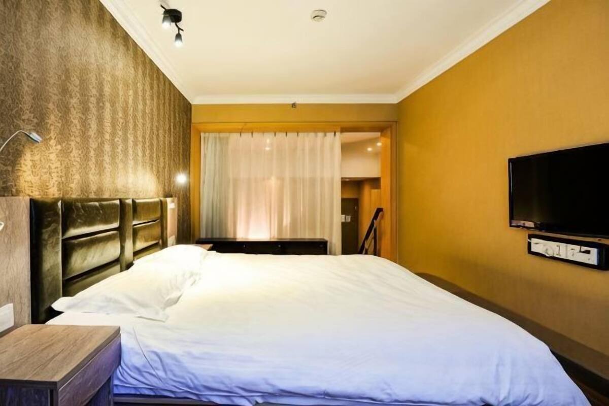 A hotel room with a bed, a television, and a desk.