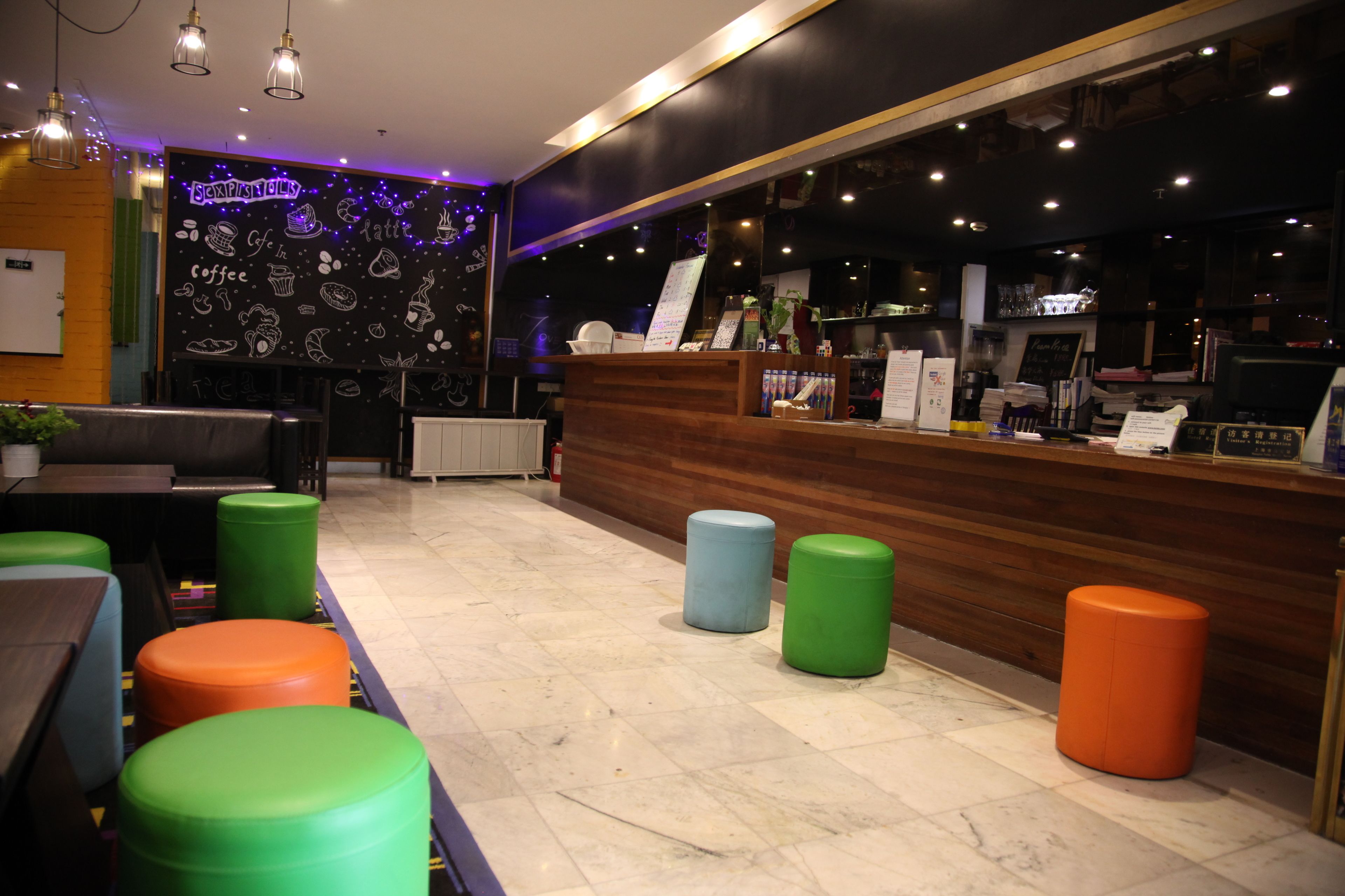 A restaurant interior with a wooden counter, colorful stools, and a chalkboard wall with doodles.