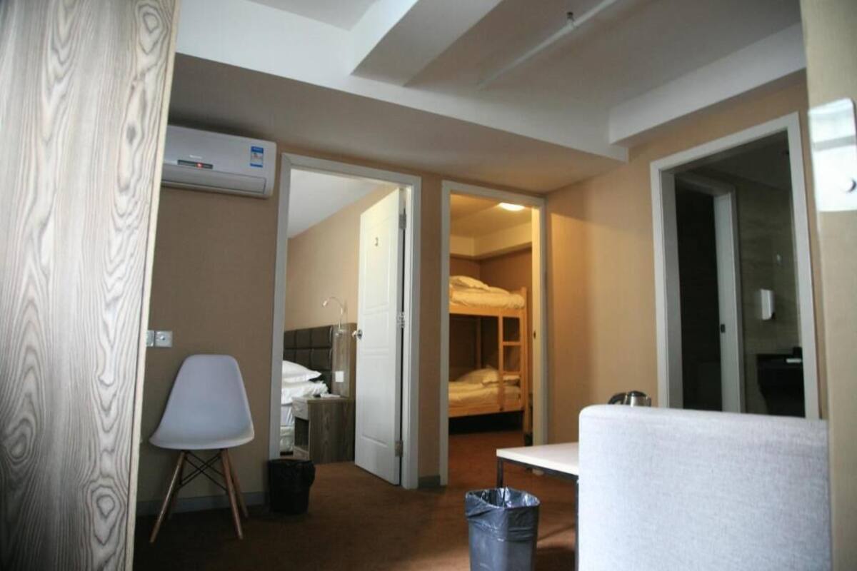 A hotel room with a bed, a chair, a table, and an air conditioning unit.
