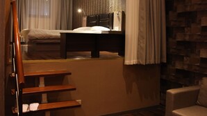 Een hotelkamer met een houten trap, een bed, een bureau en een bank.