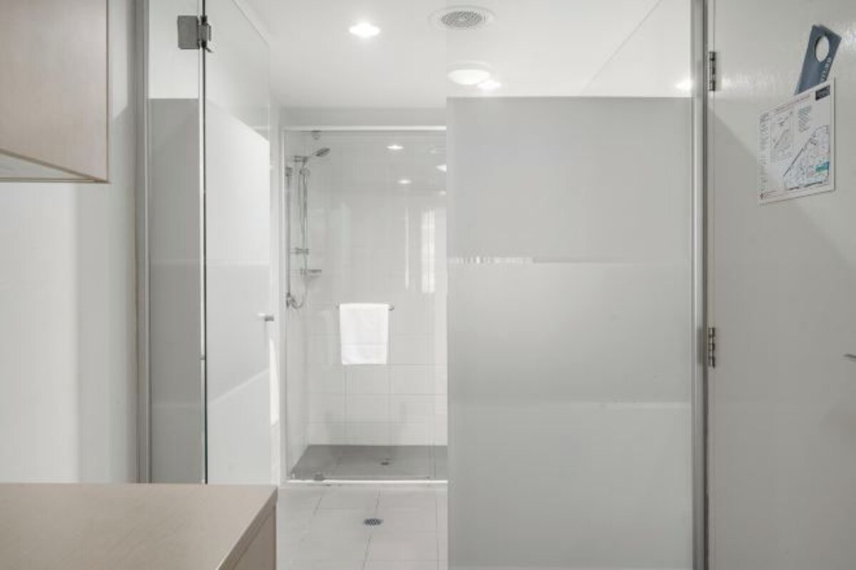 A modern bathroom with a glass shower enclosure, a toilet, and a sink.
